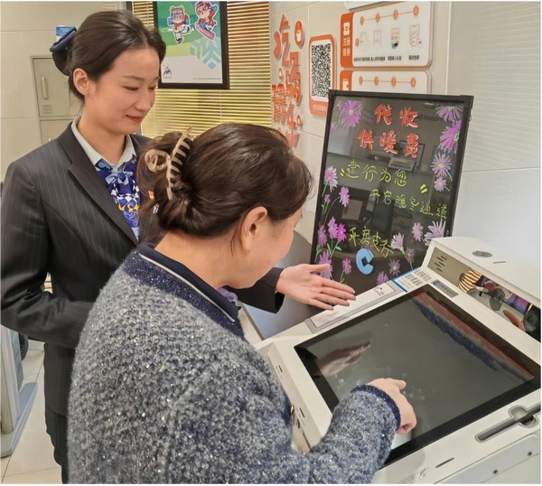 建設銀行哈爾濱平房支行大堂經理隋佳麗指導市民通過網點智慧柜員機輕松繳納熱費。